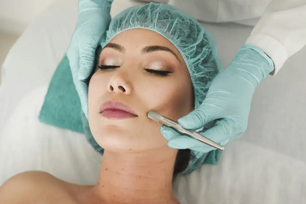 Client lying on a treatment bed while a gloved practitioner performs a facial skin treatment